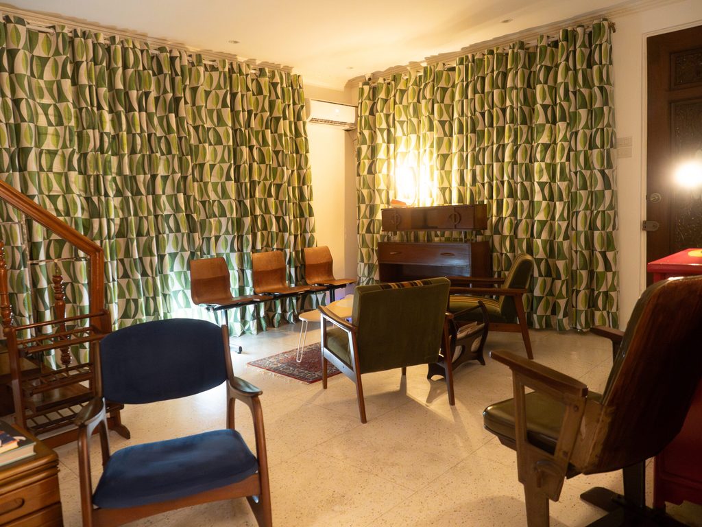 Mid-century lounge at 61 Orange with retro green curtains and vintage chairs