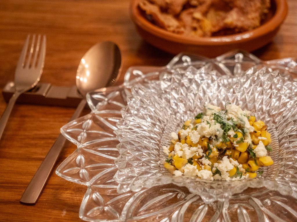 Charred corn salad with crumbled cheese in vintage crystal bowl