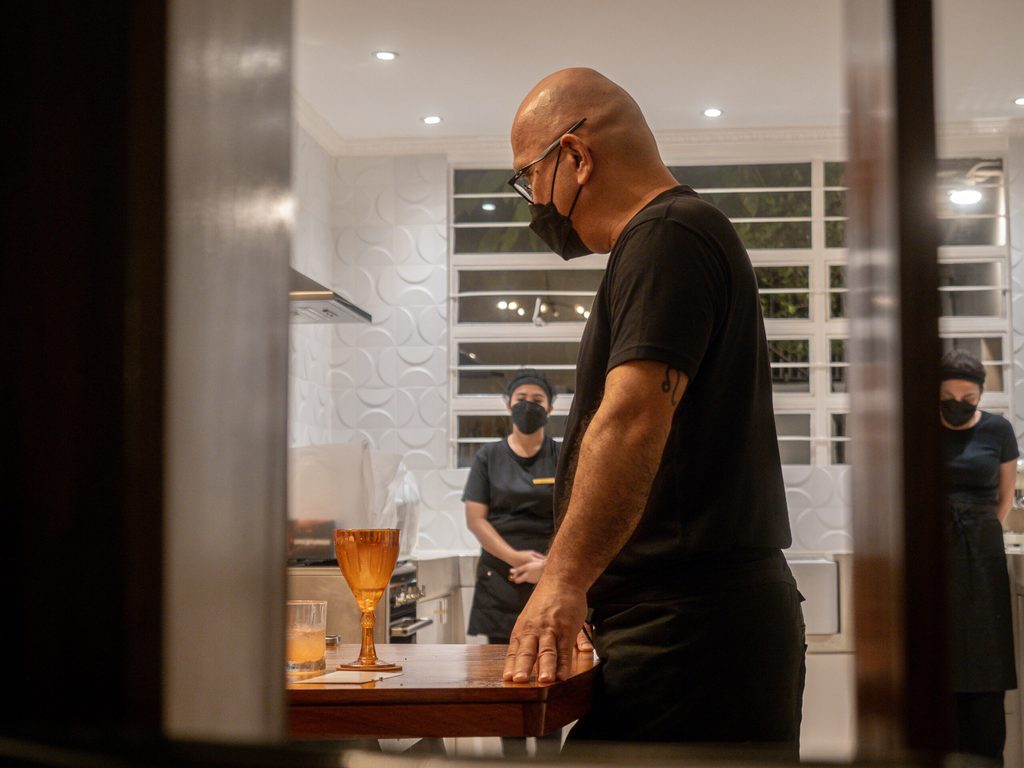 Chef Nats in the open kitchen with amber glassware in foreground