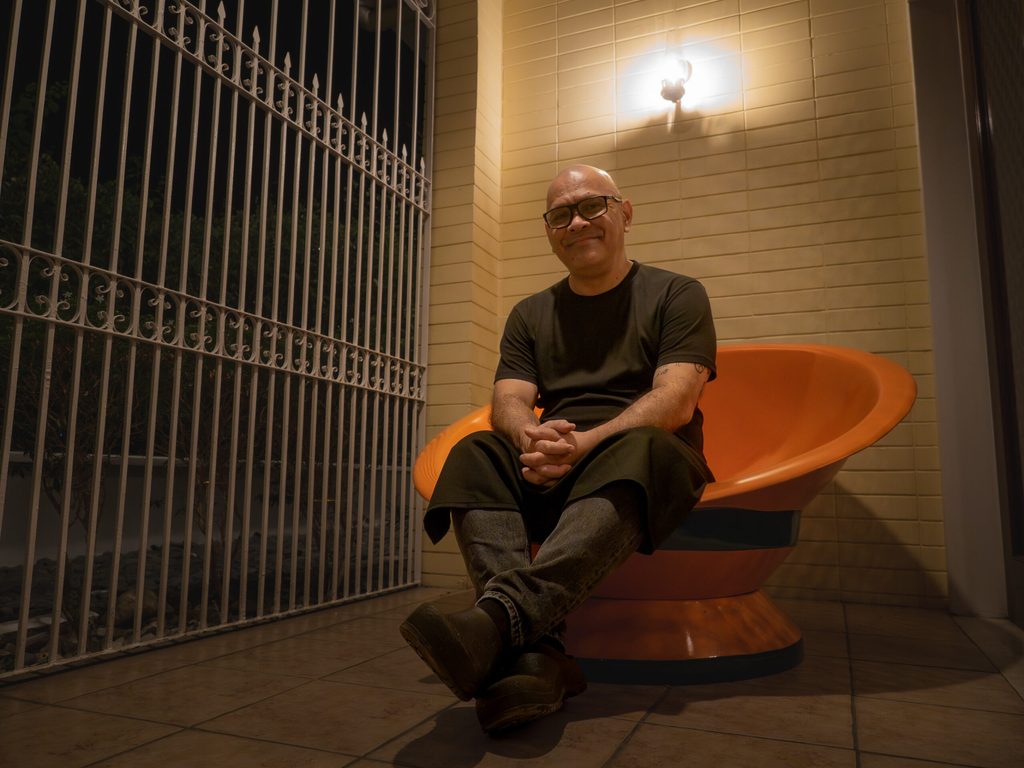 Chef Nats seated on an orange mid-century chair at the entrance